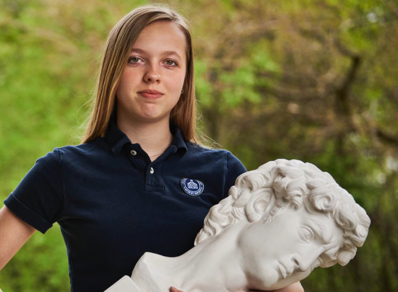 Student holding a bust of Michelangelo's David.