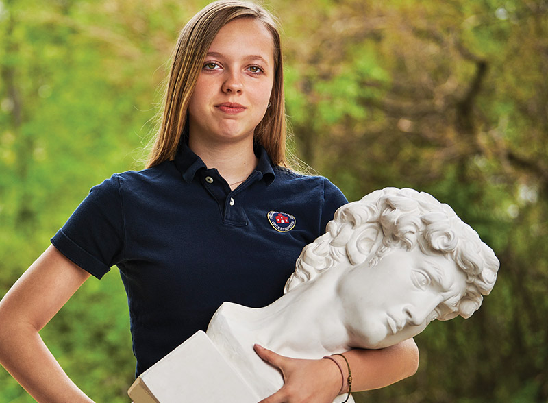 Student holding a bust of Michelangelo's David.
