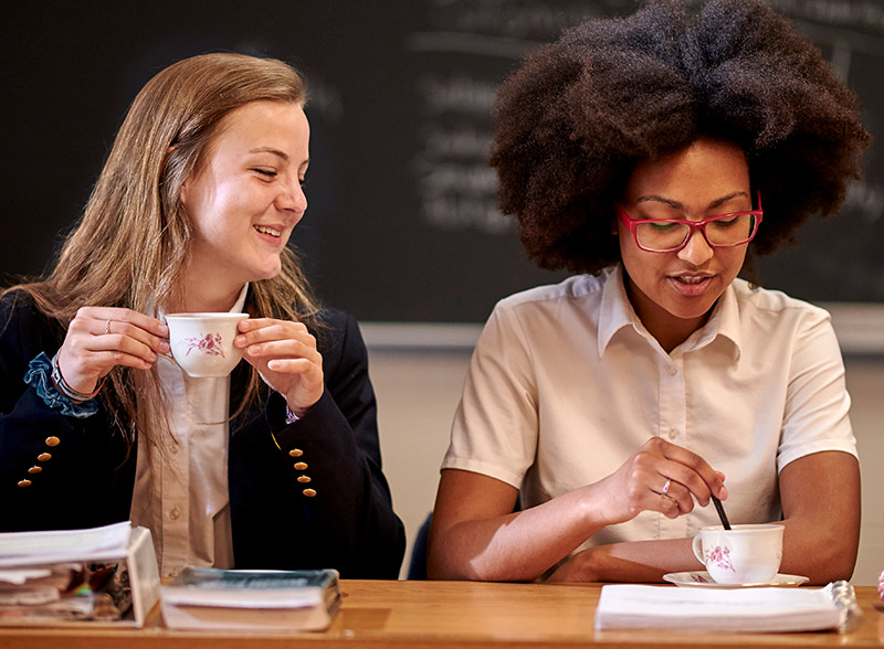 Two students drinking tea in class.